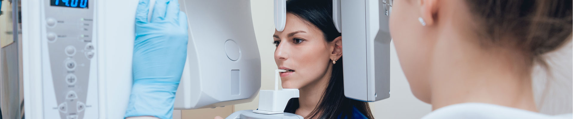 Junge Frau steht im Röntgengerät beim Zahnarzt