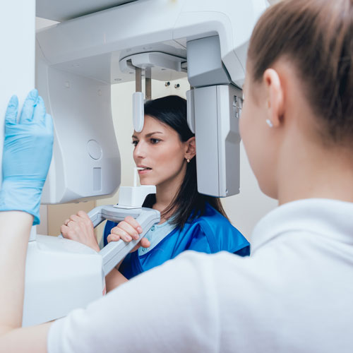 Zahnmedizinische Fachangestellte bereitet Patientin auf das Röntgen vor.